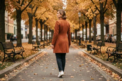 Femme de 40 ans marchant seule dans un parc en automne, vêtue d'un manteau en laine rouille, illustrant les bienfaits de la marche quotidienne sur le moral