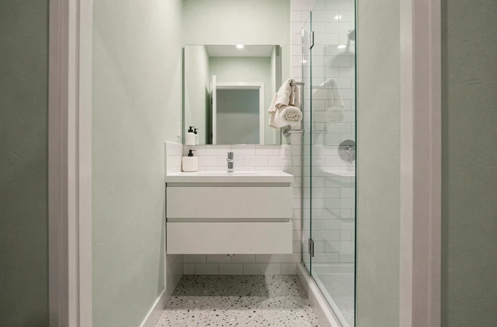 Petite salle de bain aux murs vert sauge pâle et carrelage blanc pour un effet d'agrandissement visuel